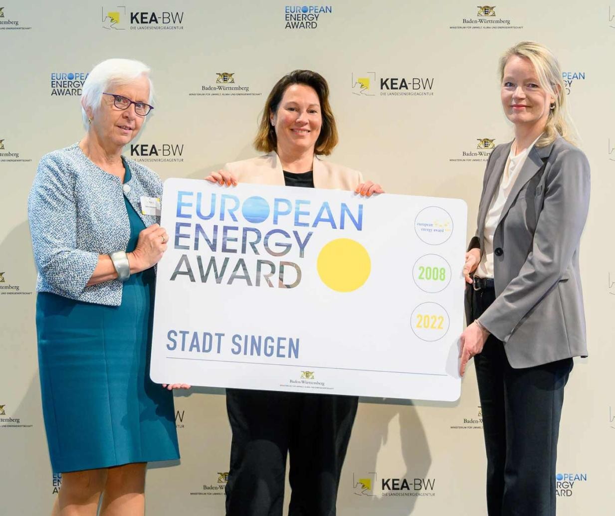 Petra Jacobi, Singens Radverkehrsbeauftragte mit dem eea-Preis in Gold (Mitte). Mit dabei: Thekla Walker, Landesministerin für Umwelt, Klima und Energiewirtschaft (rechts) und Gudrun Heute-Bluhm, Präsidentin des internationalen Vereins eea. Fot Drei Frauen und ein Schild mit der Aufschrift European Energy Award