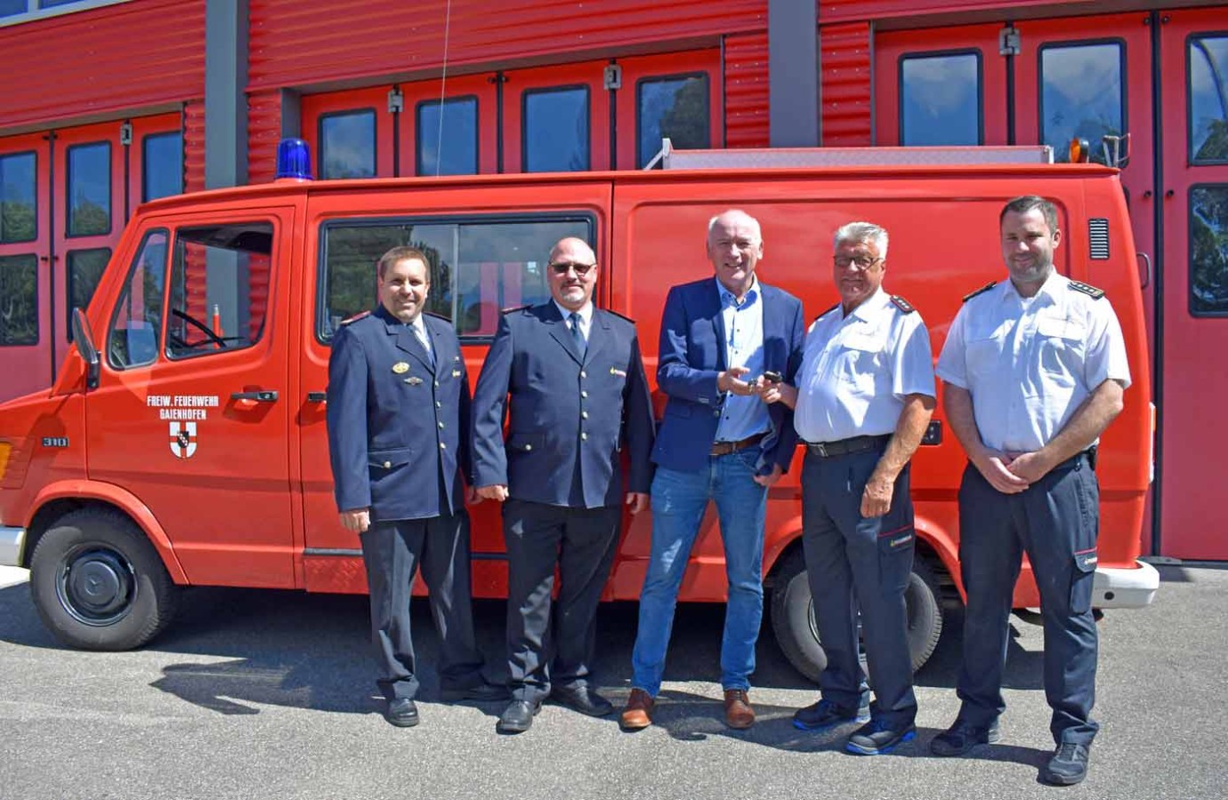 5 Männer stehen vor einem Feuerwehrwagen.