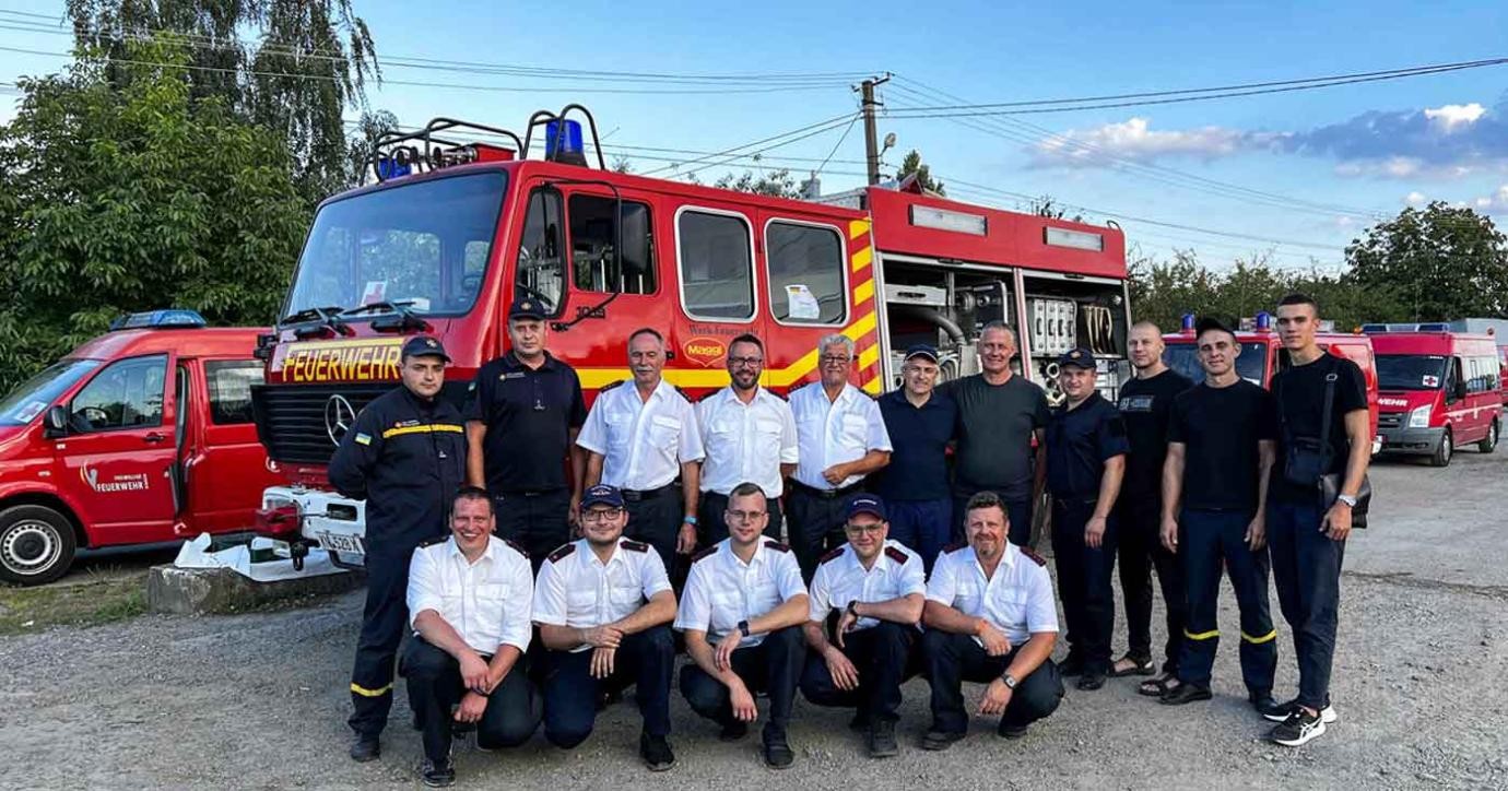 Die ukrainischen und deutschen (mit weißen Hemden) Feuerwehrkameraden bei der Übergabe der drei Fahrzeuge. Übergabe von drei Feuerwehrfahrzeugen, Gruppenbild mit 15 Männerm